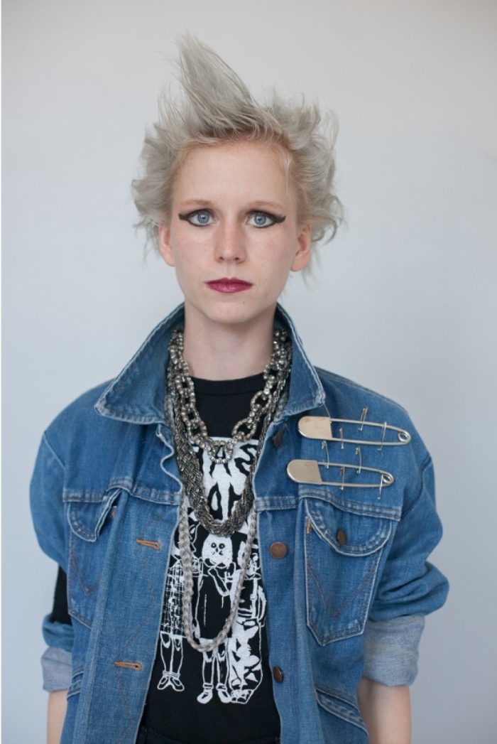 bold black eyeliner, around the eyes of a young woman, with platinum blonde messy hair, and dark red lipstick, couples halloween costume ideas, black t-shirt and denim jacket, with safety pins, and chunky necklaces