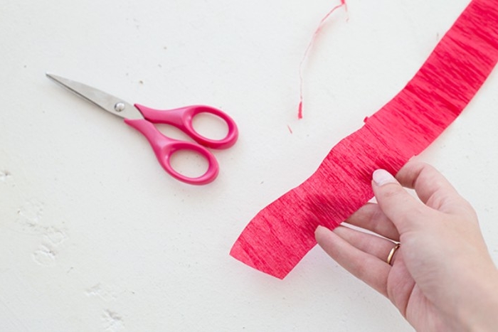 red strip of tissue paper, cut so it looks wavy, and held by a pale hand, couples halloween costumes, diy pizza outfit, a pair of scissors nearby