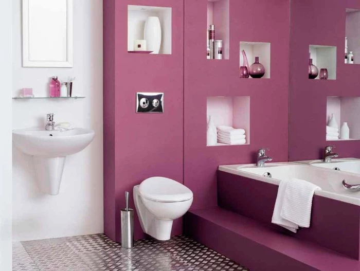metallic silver floor, in a white room, with a dark pink, bathroom accent wall, a sink and a mirror, a toilet and a tub