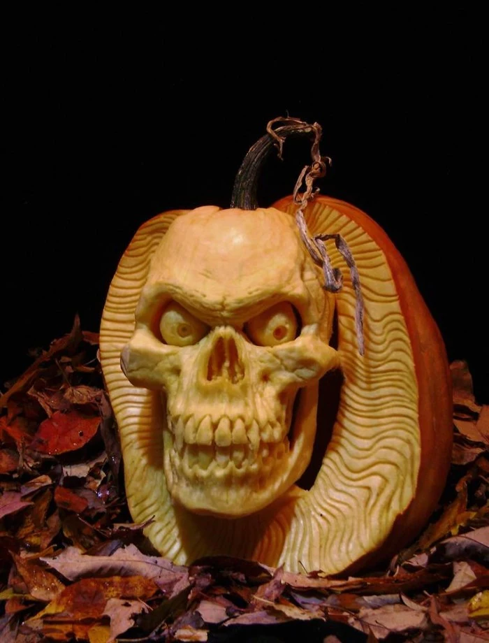 skeleton pumpkin, detailed and realistic carving, of an evil skull, made from an orange pumpkin, placed on a bed of red fall leaves