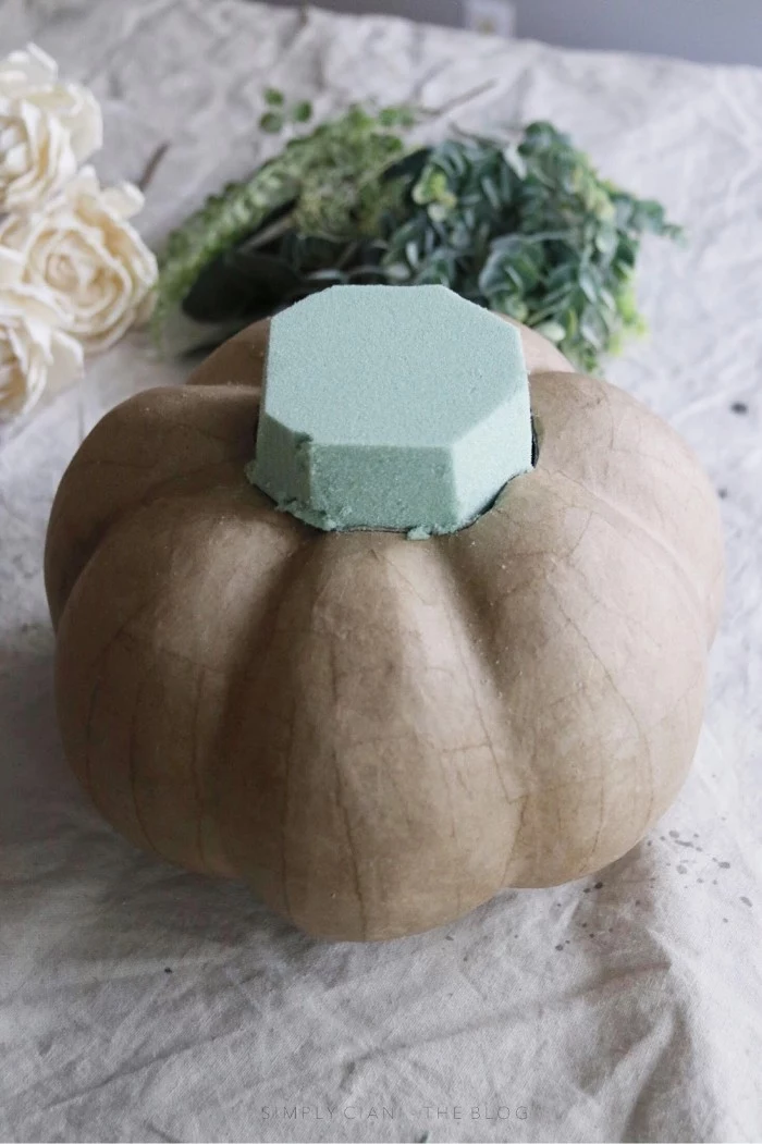 shaping a mint green florist sponge, and placing it inside a hole, cut on top of a beige, papier mache pumpkin, dollar store crafts, to try at home