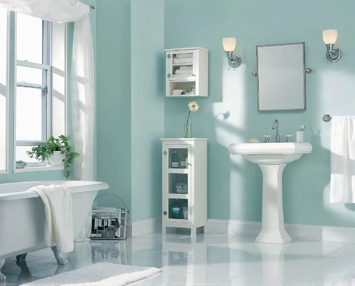 light blue walls, inside a bright room, with a bathtub, a sink and two small cupboards, bathroom color schemes, smooth white tiled floor