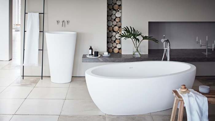 smooth oval bathtub, inside a room in pale cream and light grey, with a modern sink, and decorative wooden elements, master bathroom remodel