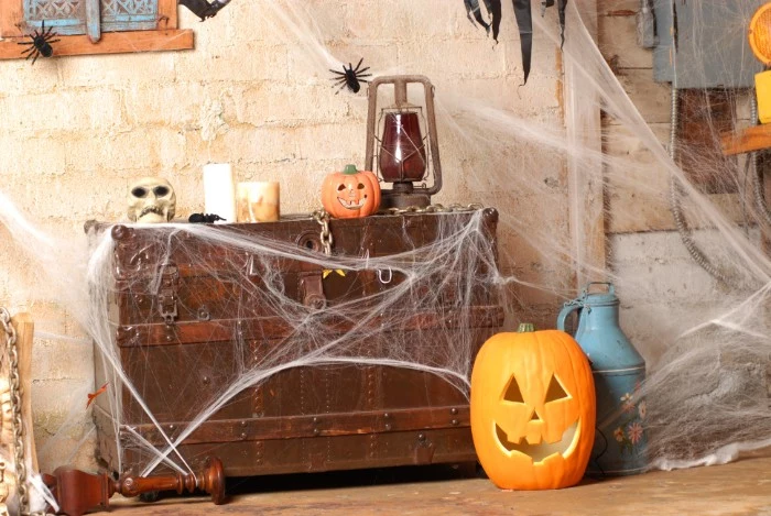massive brown wooden chest, decorated with fake cobwebs, a skull and an antique gas lamp, candles and black plastic spiders, haunted house decorations, jack-o-lantern ornament on the floor