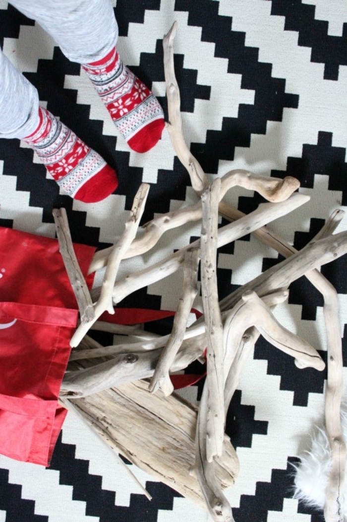 fair isle christmas themed socks, worn by two feet, standing on a black and white tiled floor, next to a pile of pale driftwood, how to decorate your room, using natural materials