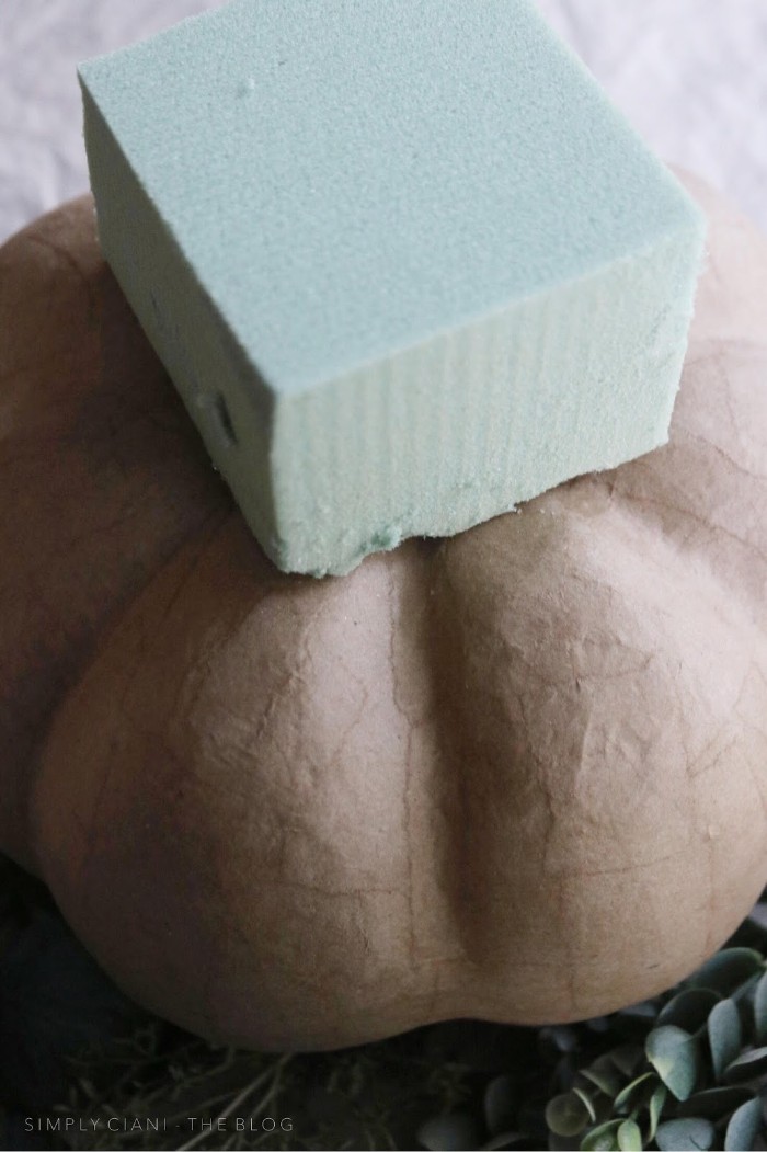 rectangular mint green florist sponge, placed on top of a pale beige, papier mache pumpkin, dollar store crafts, for decorating your home