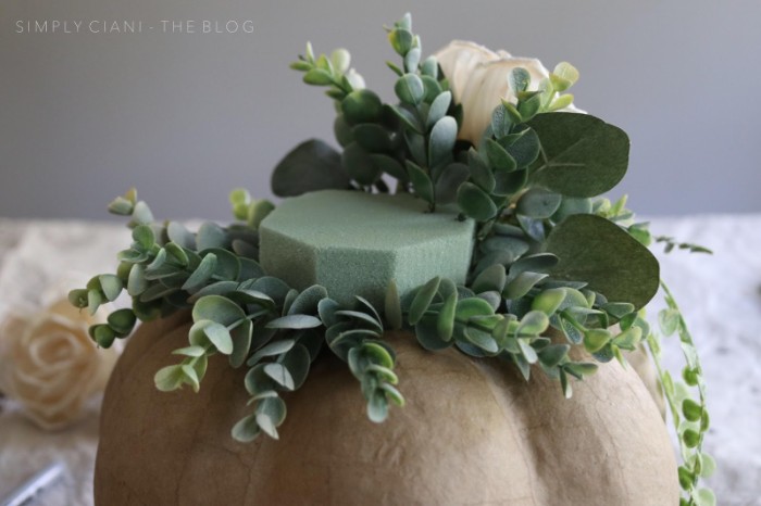 diys for your room, papier mache pumpkin in light beige, with a florist sponge on top, decorated with faux roses, and green plants