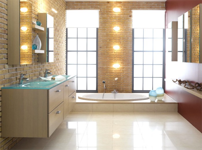 brick walls inside a bathroom, with smooth pale cream tiled floor, containing a bathtub, lamps and several cupboards
