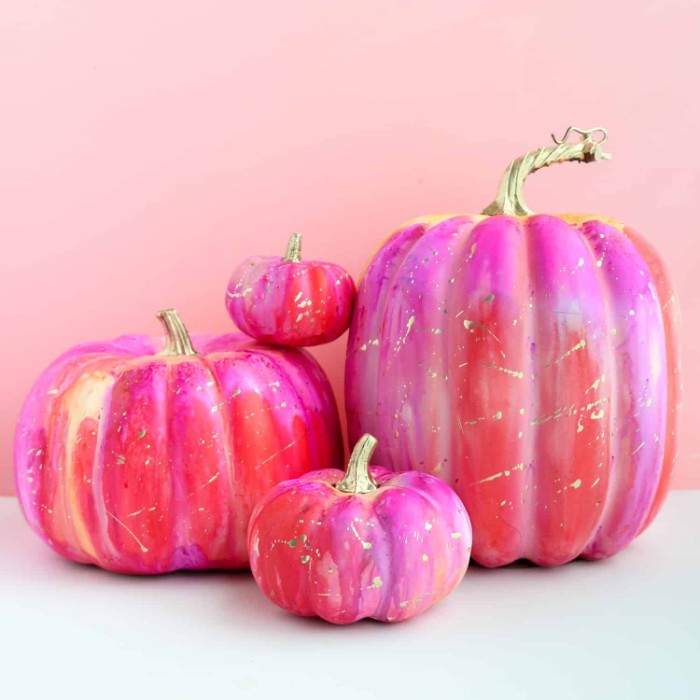 halloween decorations, four pumpkins in different sizes, covered in fuchsia pink, red and purple paint, with speckles of white and blue