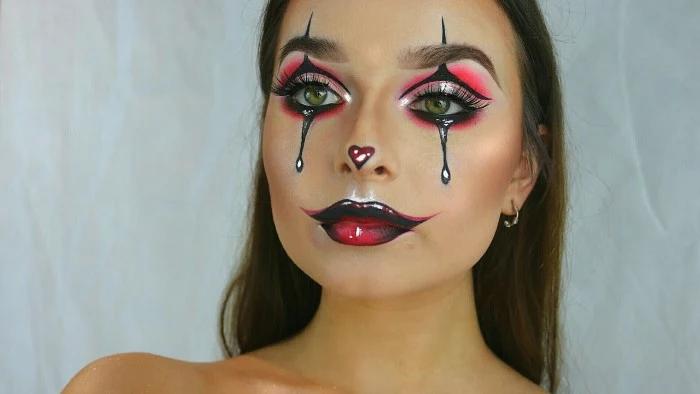 another harlequin inspired face paint, with glossy effect, neon pink eye shadow, and dark red lipstick, with black details, and a small heart shape, on the tip of the nose