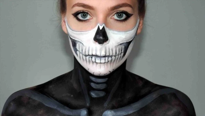 eyeliner in black, worn by a young woman, the lower half of her face is painted to look like a skull, her shoulders are covered in black and grey paint