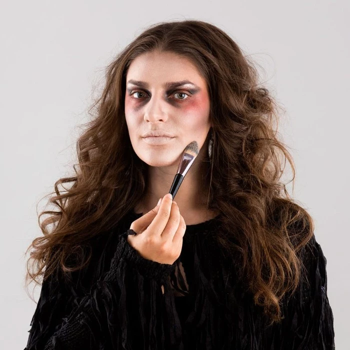 contouring the face of a young brunette woman, using makeup and a brush, zombie face paint, halloween tutorial