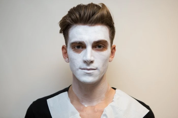 man with brunette hair, styled in a quiff, wearing white paint on his face, facepaint ideas, easy skeleton makeup tutorial