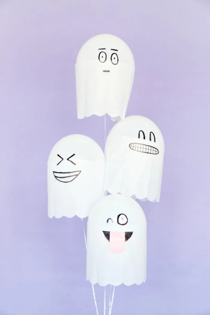 bunch of white balloons, decorated with white paper, to look like ghosts, with silly hand-drawn faces
