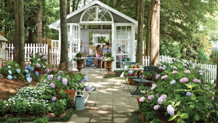 mother and young daughter, sitting in a shed, made of white wood and glass, in a garden with lots of flowers, she shed ideas, orangery style building