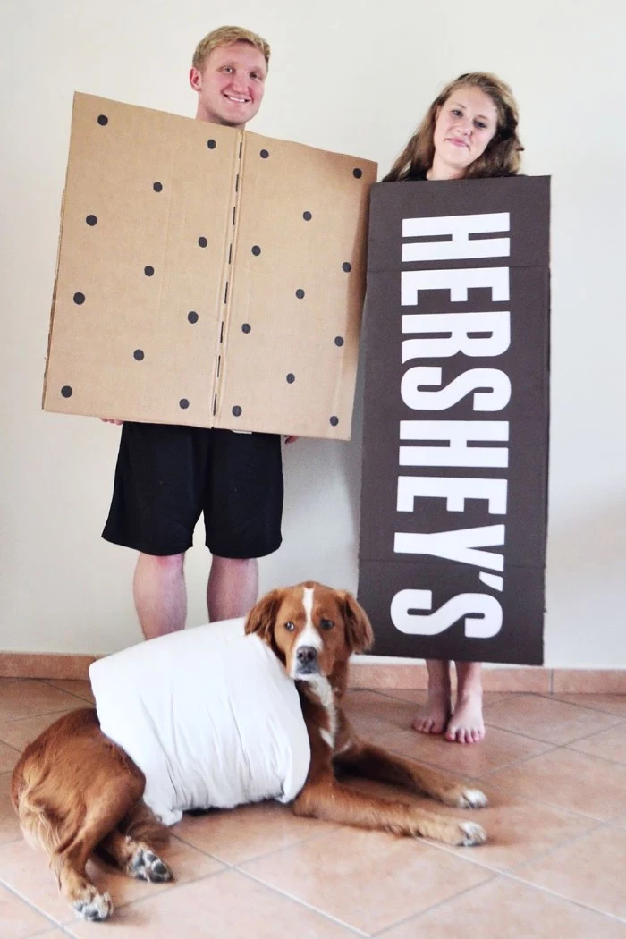 dog dressed like a marshmellow, near a man in a cracker costume, and a woman dressed like a hershey's chocolate bar, quick halloween costumes, for couples and pets