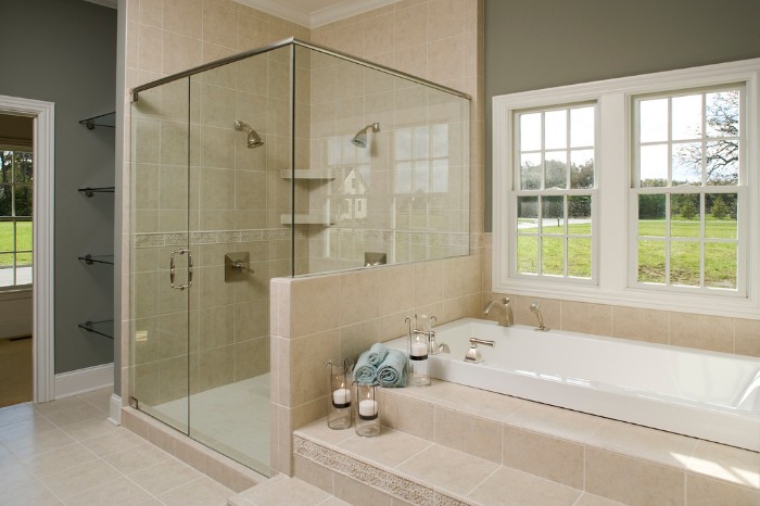 cream tiles decorating a room, with khaki green walls, and white paneling, master bathroom remodel, glass shower cabin, and an elevated tub