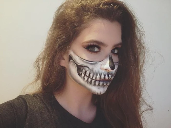 half skeleton face paint, worn by a young woman, with long brunette hair, wearing fake lashes, and black eyeliner