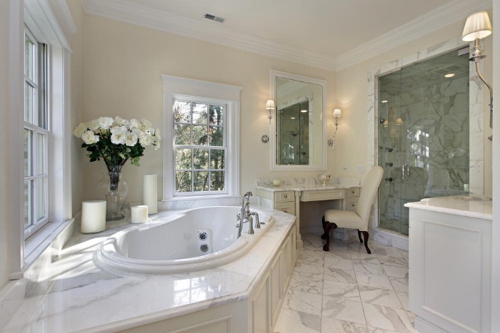 classic bathroom with marble floor, vintage white furniture, antique vanity with an off-white chair, round elevated bathtub, and a bouquet of white flowers