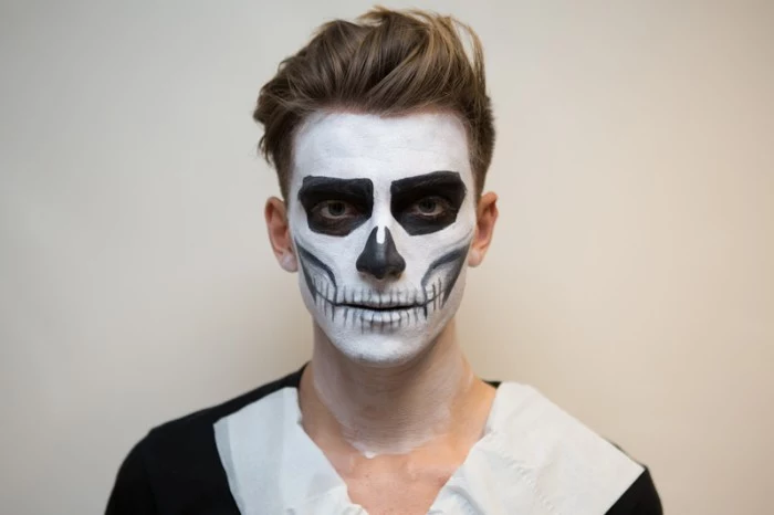 jaw bones and teeth, and other skeleton features, drawn on the face of a young man, with black and white paint 