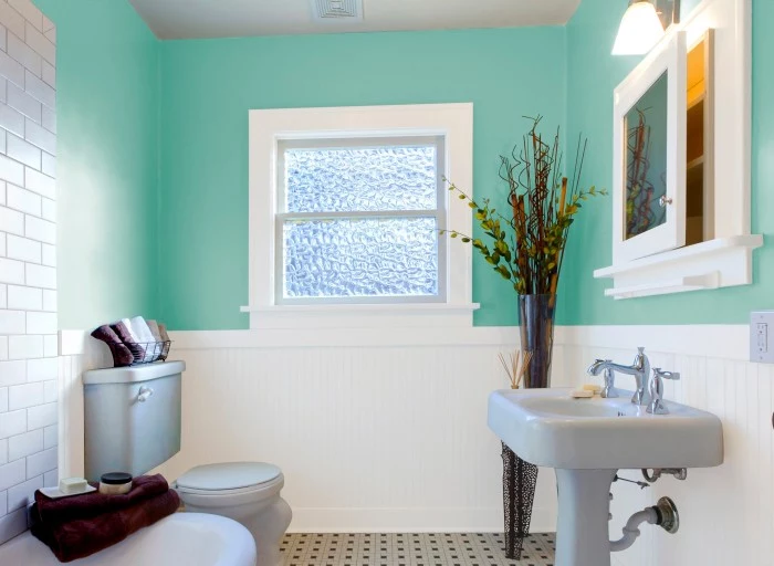 plants in a tall vase, decorating a teal blue bathroom, with white wooden paneling, and baby blue sink and toilet set, small bathroom paint colors, small window and white subway tiles