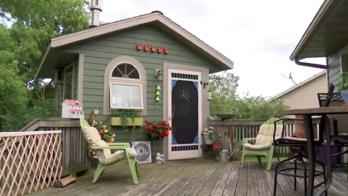 deck made of wood, with a small pastel green shed, featuring a door and a wndow, garden shed ideas, two light green garden chairs nearby