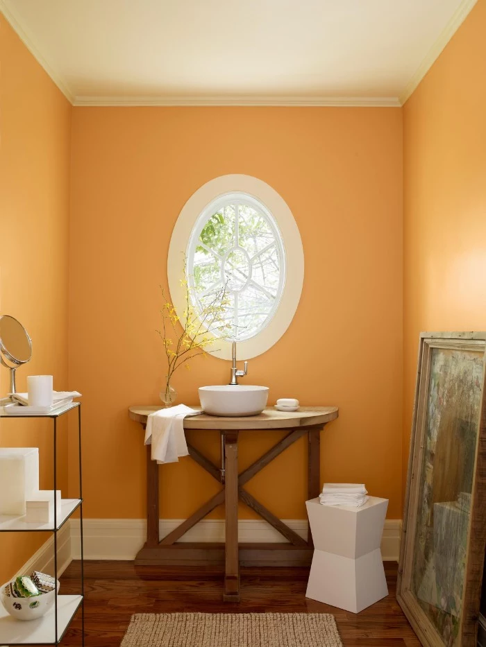 pastel orange room, with an oval window, a white ceiling, and a dark brown wooden floor, bathroom color schemes, modern sink on a wooden stand