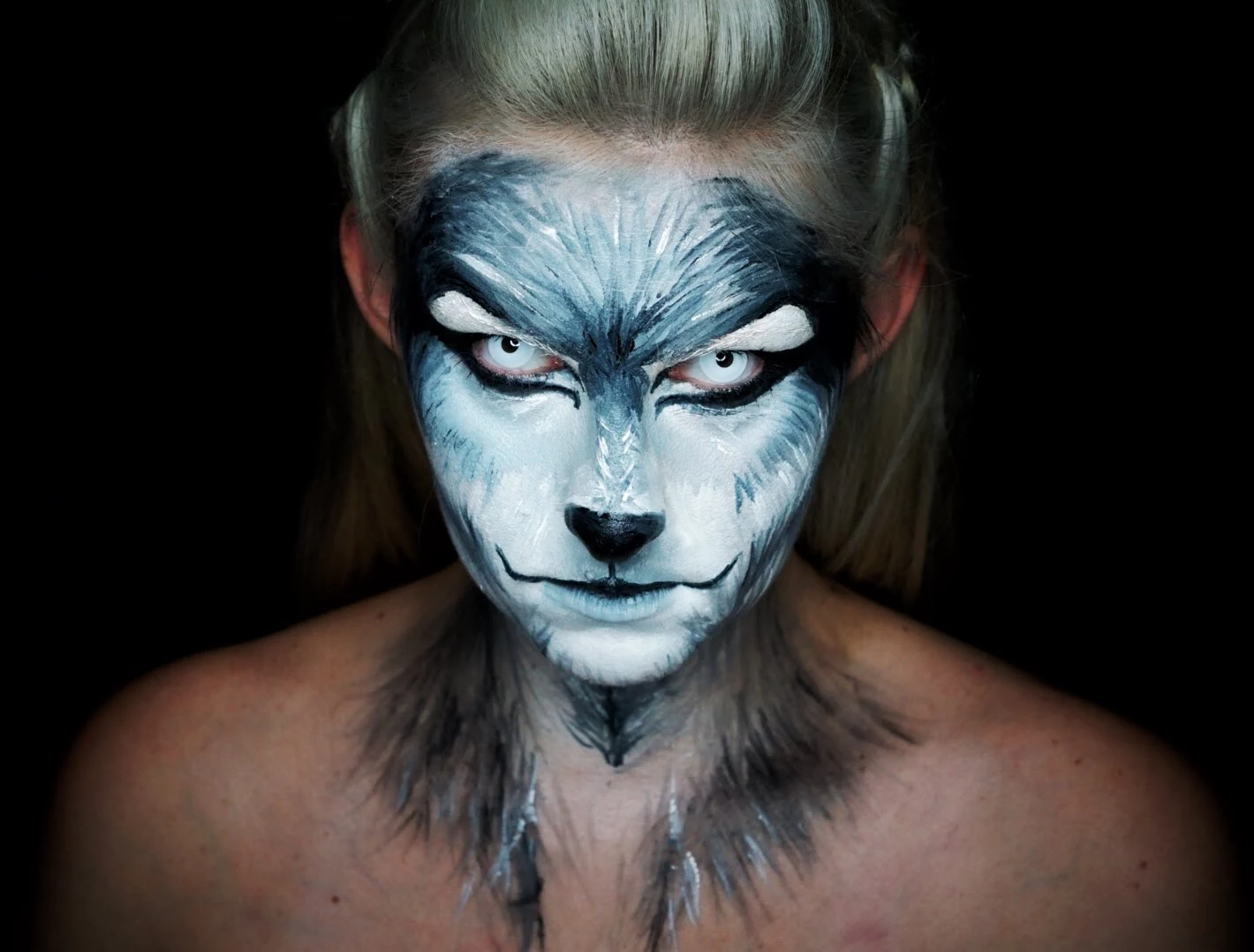 werewolf face paint, in white and grey, worn with pale blue contact lenses, by a blonde woman, halloween face paint 