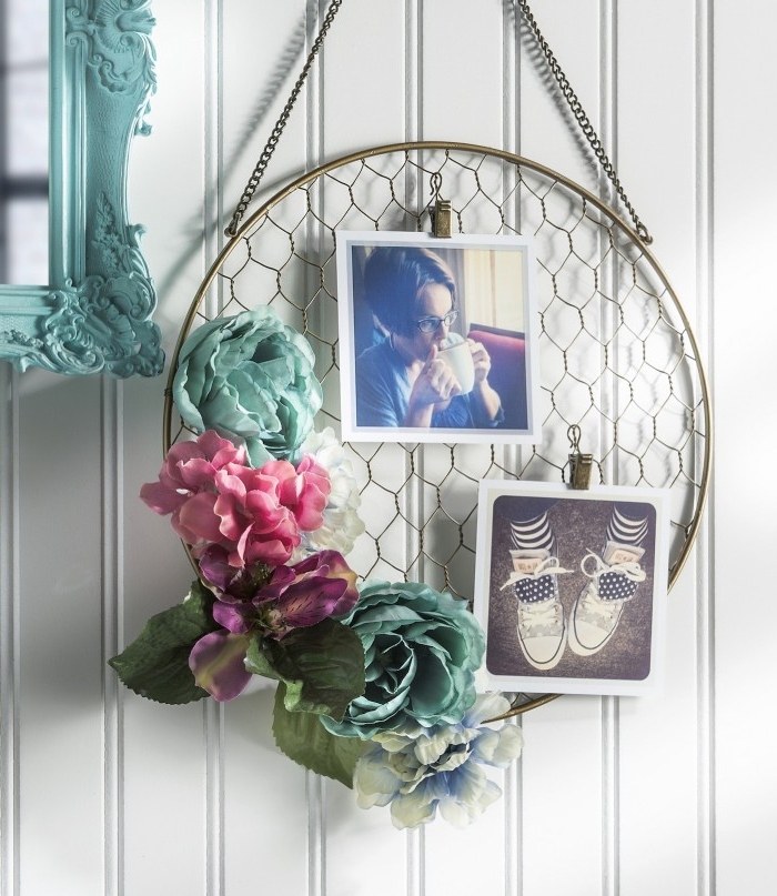 oval wall decoration, made from a metal hoop, and mesh net, and decorated with two photos, and some faux flowers