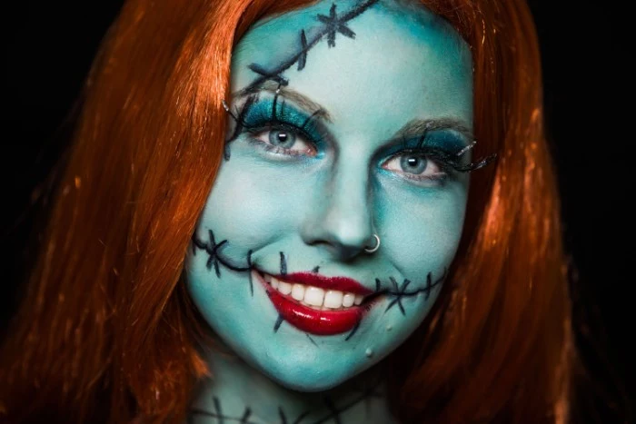 nightmare before christmas-inspired face paint, woman dressed like sally, in a ginger wig, wearing pale blue paint on her face, with black hand-drawn stitches, and glossy red lipstick