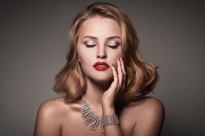diamond necklace and matching bracelet, worn by a young pale woman, with wavy dark blonde, shoulder length hair, christmas eyeshadow with smokey effect, glossy red lipstick