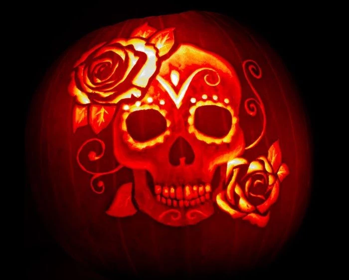 roses and a skull with ornaments, carved on an orange pumpkin, lit with candles from within, skeleton pumpkin, inspired by dia de los muertos