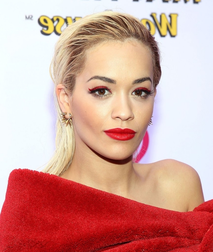 rita ora with slicked back wet-look blonde hair, wearing red eyeliner, and red lipstick, eye makeup for red lips, dressed in a plush red top