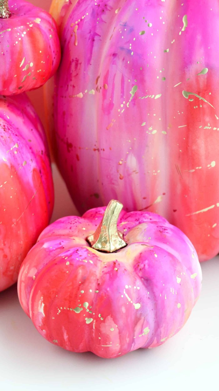 finished painted fake pumpkins, covered in red and fuchsia pink paint, halloween pumpkin decorations, with splatters of gold paint