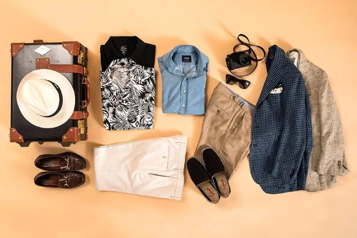 holiday capsule wardrobe men, two blazers and two pairs of trousers, in light colors, three button up shirts, loafers and espadrilles, a hat and sunglasses