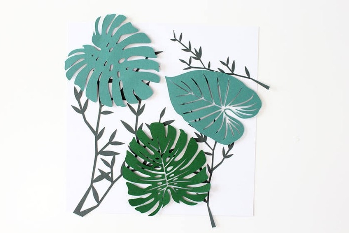 three different palm leaf shapes, cut out from paper in different shades of green, and stuck on top of a white piece of paper, with dark green branch-like shapes, diy bedroom décor