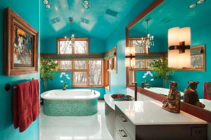mosaic tiles in different shades of blue, covering the outside of a bathtub, in a spacious room, with turquoise walls and ceiling, best bathroom paint colors, window and a large mirror
