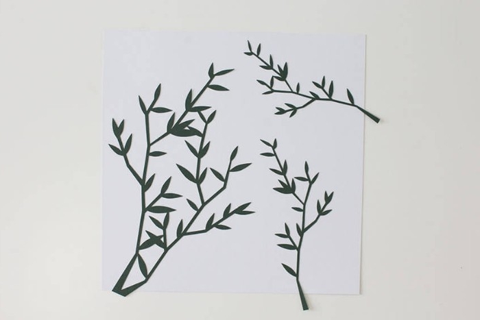 diy bedroom décor, for your walls, three dark green, branch-shaped paper cutouts, stuck on a white, square piece of paper, 