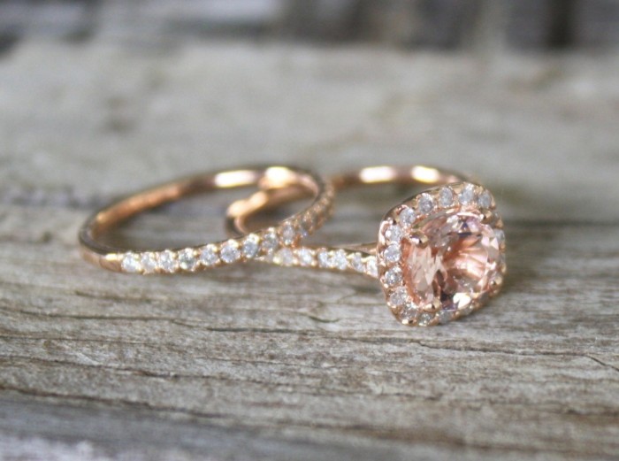 close up of two gold rings, one features a large pink diamond, and several small white diamonds, and the other is encrusted in small white diamonds