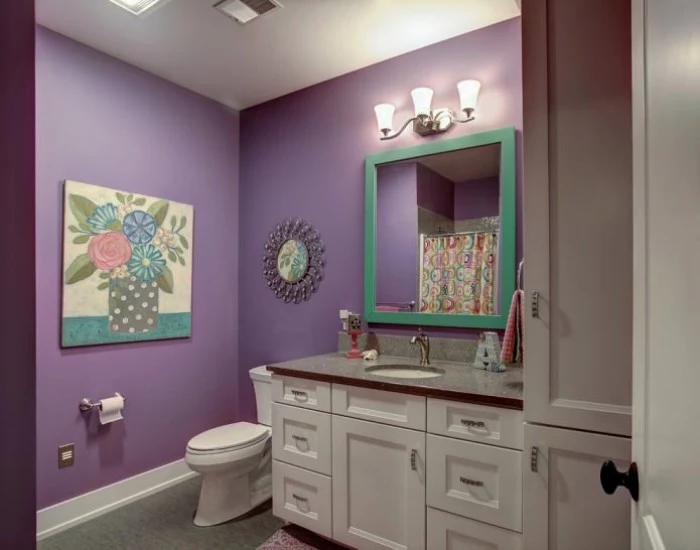 painting of a flower vase, decorating the violet walls of a room, with white furniture, a toilet and a large, square mirror in a turquoise frame, small bathroom paint colors