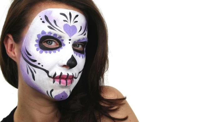 heart shape and floral motifs, decorating a sugar skull face paint, in white and black, pink and violet, on the face of a brunette woman