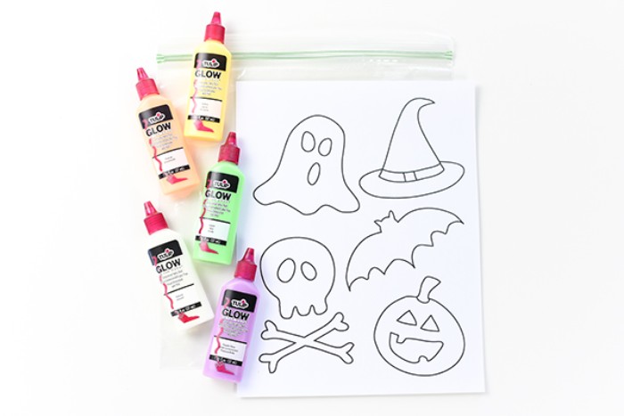 materials needed for creating diy, glow-in-the-dark stickers, halloween decorations, five small tubes of glow-in-the-dark paint, a clear zip bag, and a piece of white paper, with halloween-themed shapes