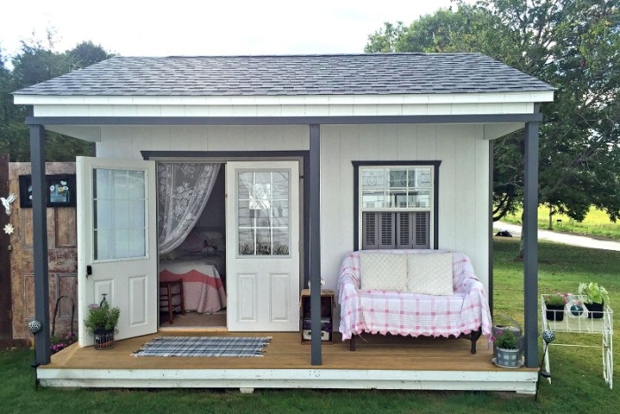 sofa in pale pink and white, on the porch of a small house, in white and dark grey, she shed images, oneof its double doors is open