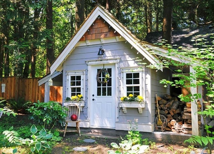 forest hut made of wood, painted in pale grey, white and brown, with two little wndows, and a foor, she shed images, surrounded by trees