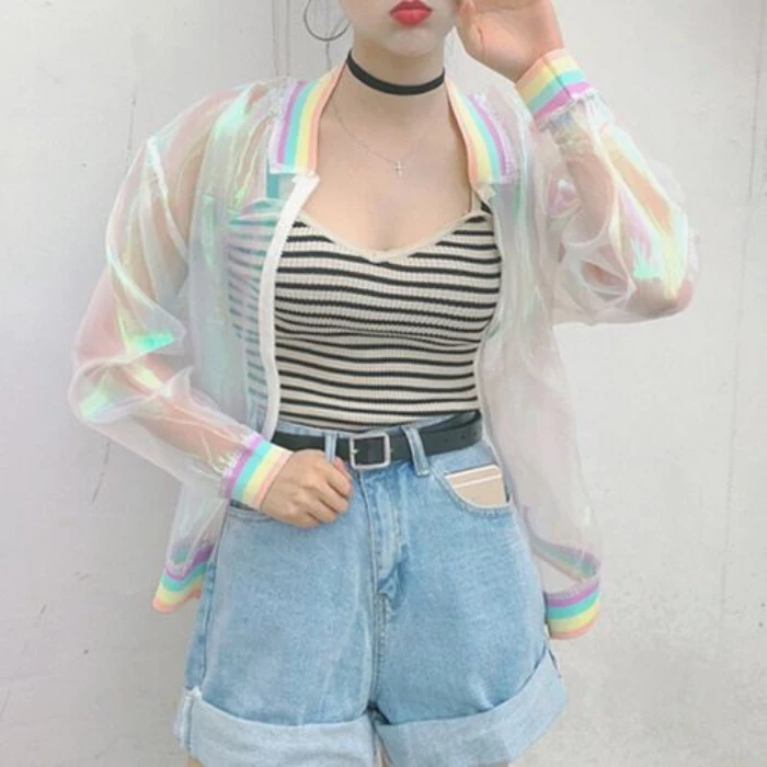 iridescent transparent baseball jacket, with pastel rainbow details, worn over a striped black and white tank top, and pale blue, acid wash high wasited denim shorts, 90s and 80s grunge inspirations