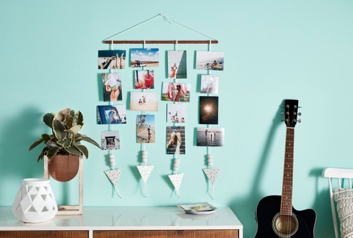 photos hanging on strings, attached to a small wooden pole, hung on a pale blue wall, near a potted plant, and a guitar, teenage girl room ideas