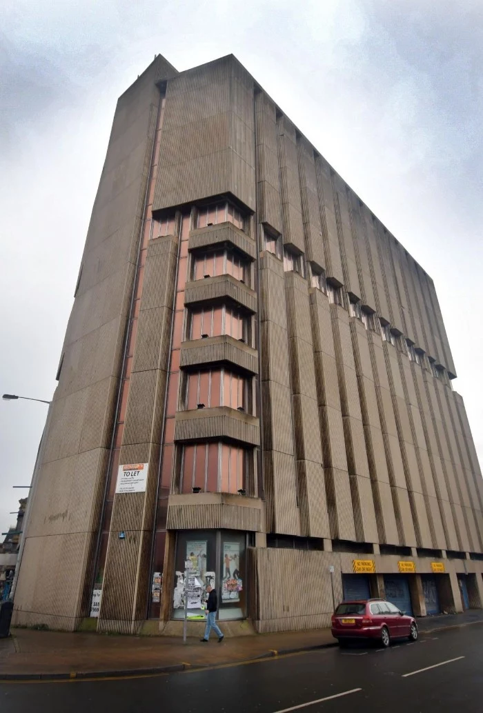 high point building, in bradford england, old beige concrete structure, with brown reflective wondows