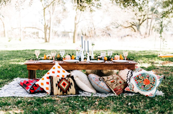 cushions in various colors, with different patterns, next to a wooden table, decorated for a fancy meal, and placed in a garden, 50th birthday ideas