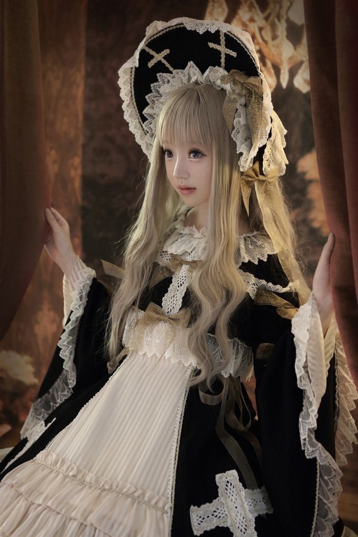 cross motifs on a black bonnet, decorated with white lace trims, worn by a girl, in a long ash blonde wig, with a black and white lolita dress, featuring bell-shaped sleeves, frills and bows
