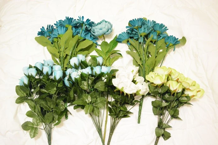 six bouquets of faux flowers, in pale blue and teal, white and pale yellow, diys for your room, placed on a white fabric